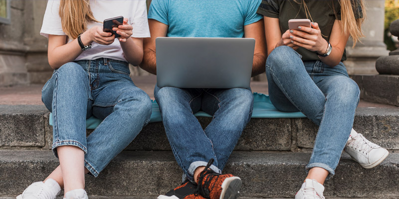 3 teens sitting browsing social media on cell phones