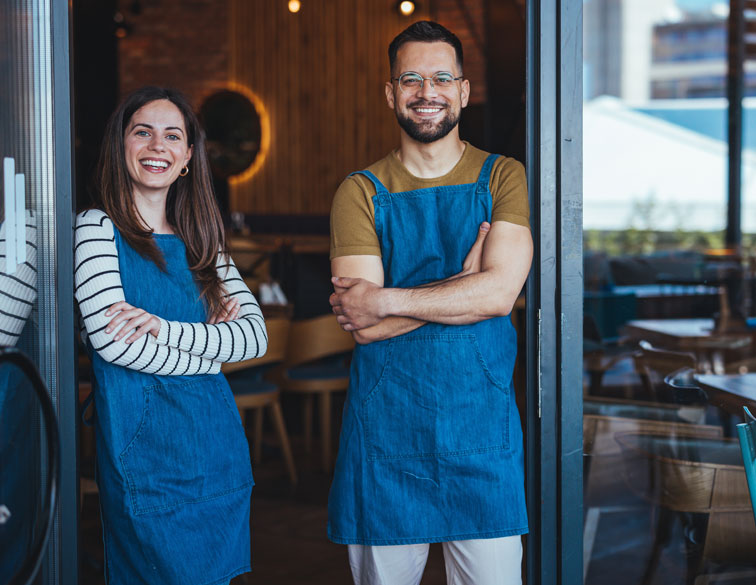 small business owners stamding outside of store front together smiling