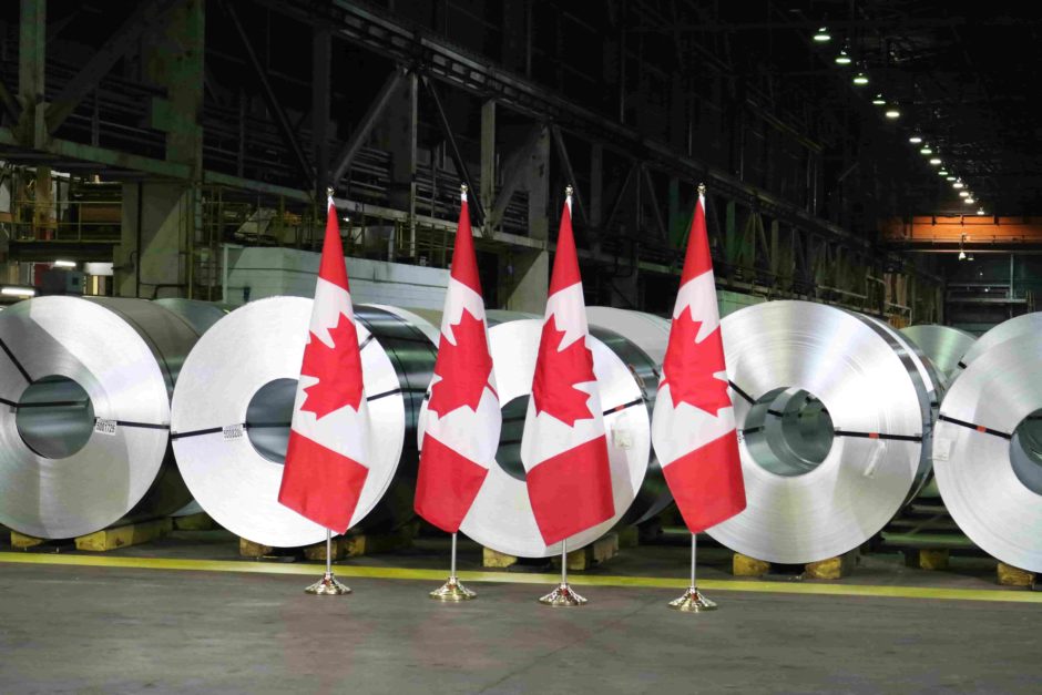 four Canadian Flags in front of five large stainless steel coils