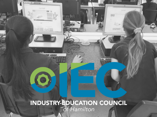 gray image of two girls working on a computer with IEC logo at the bottom