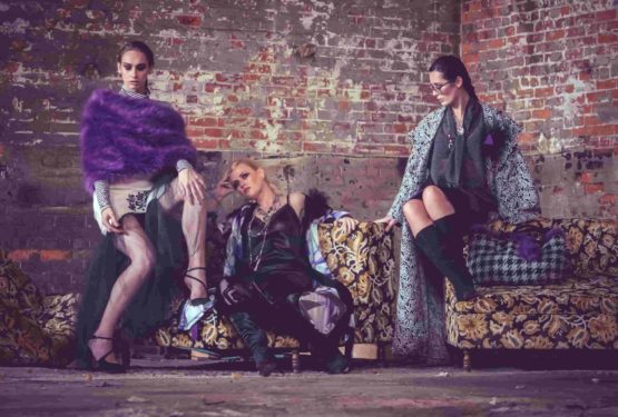 three fashion models seated in front of brick wall