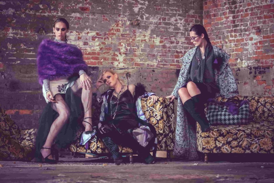 three fashion models seated in front of brick wall