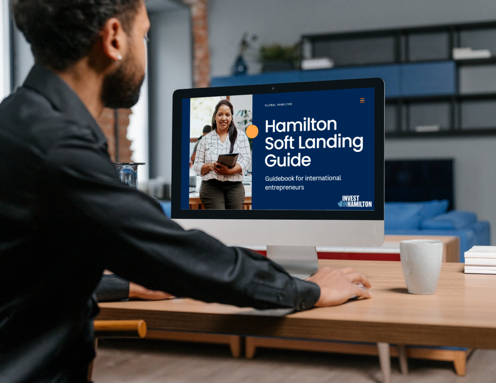 Man sitting at a desk looking at a computer screen displaying the Hamilton Soft Landing Guide website.
