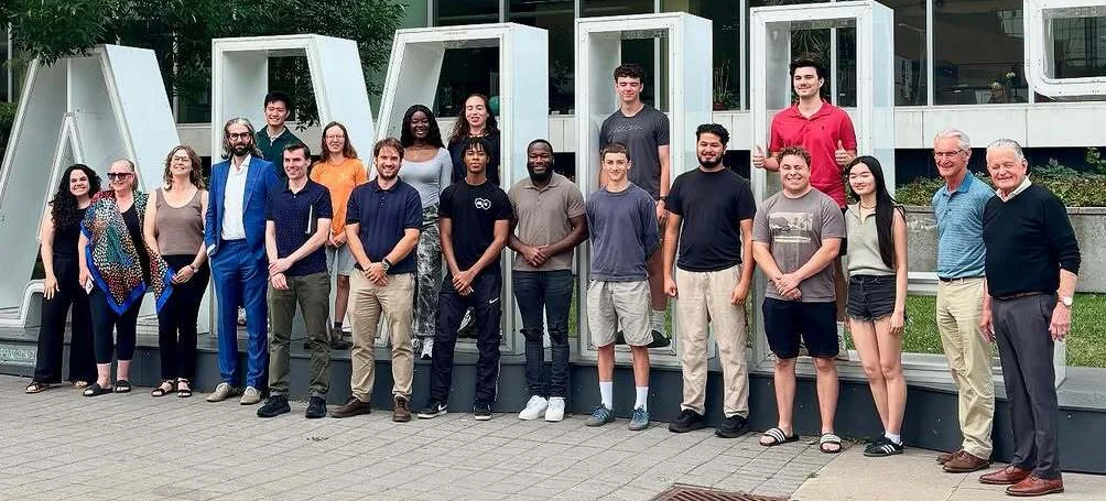 A group of people posing together outside in front of large block letters spelling "WATERLOO.