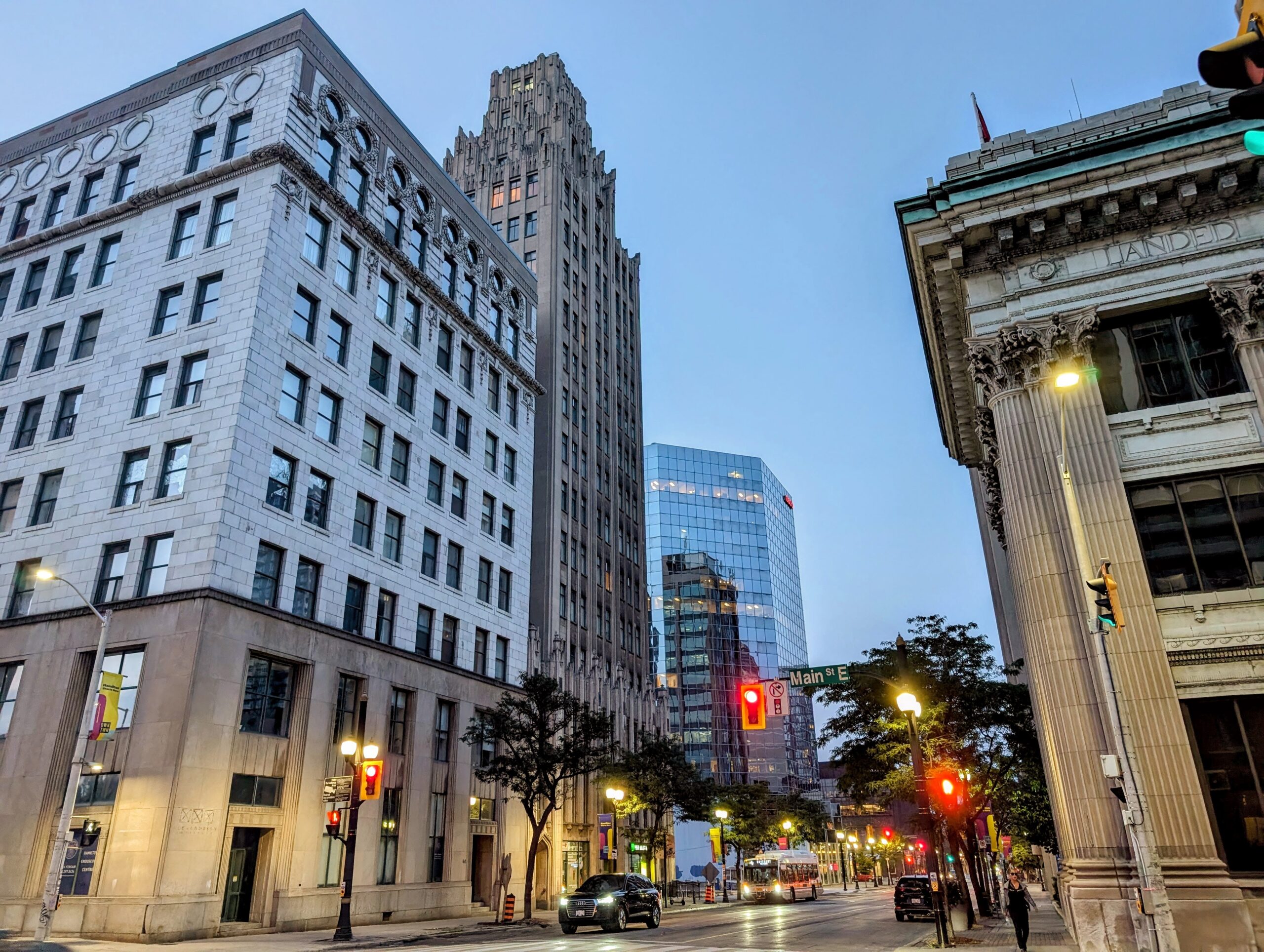 A street of downtown hamilton, ontario, at dusk. A mix of modern and historical buildings.