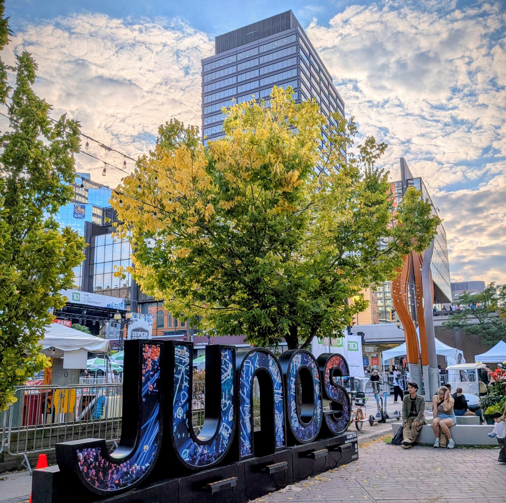 Giant letters spelling JUNOS as an art display during Supercrawl in Hamilton, Ontario with the blue sky and a few clouds in the background